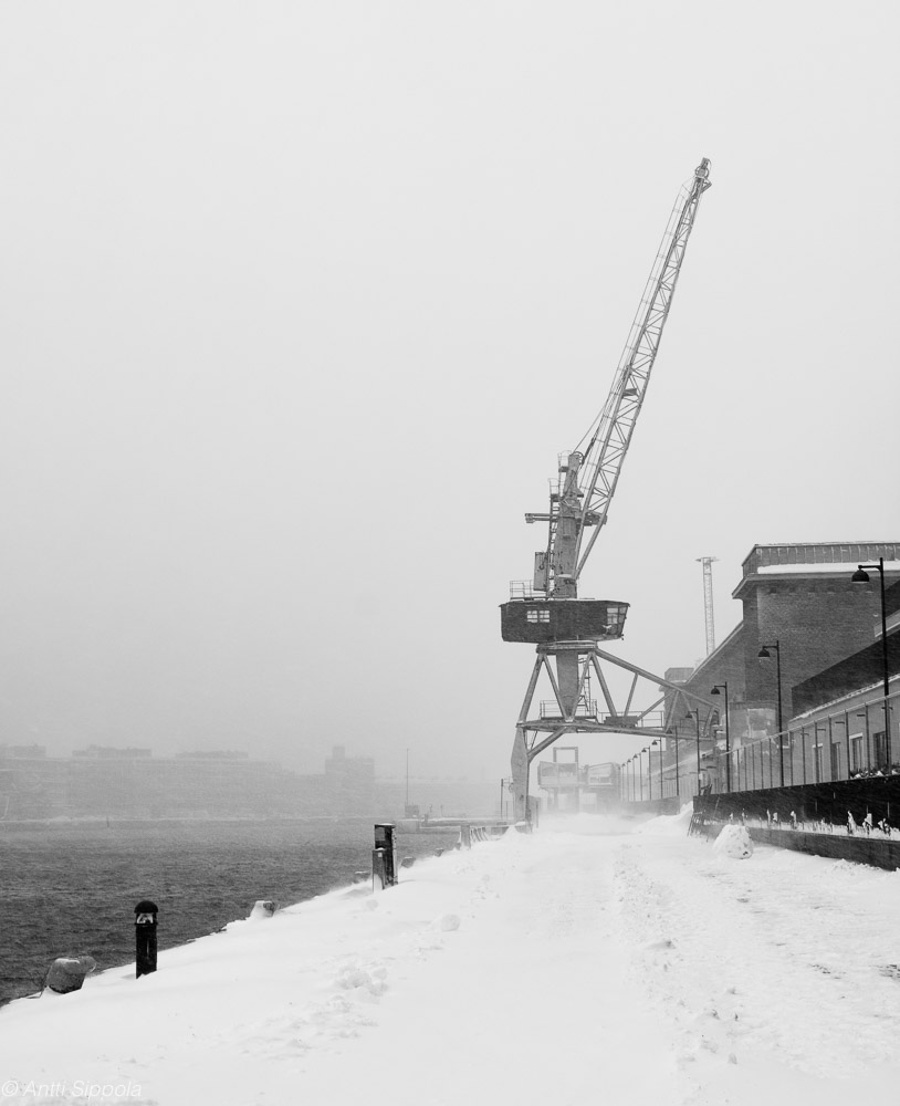 An old harbor crane in a snow storm.