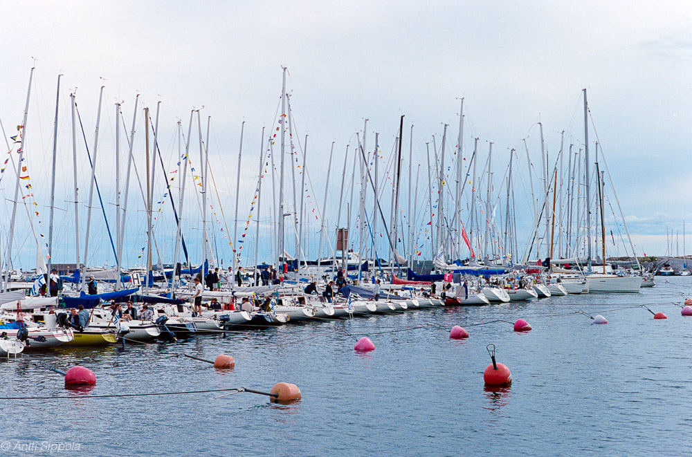 A row of sailing boats docked in a small boat harbor.