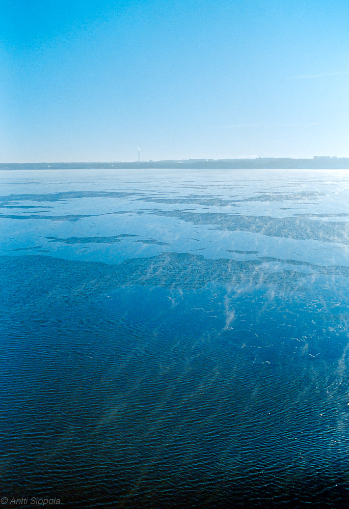 Streaks of sea smoke drifting over a partly frozen sea.